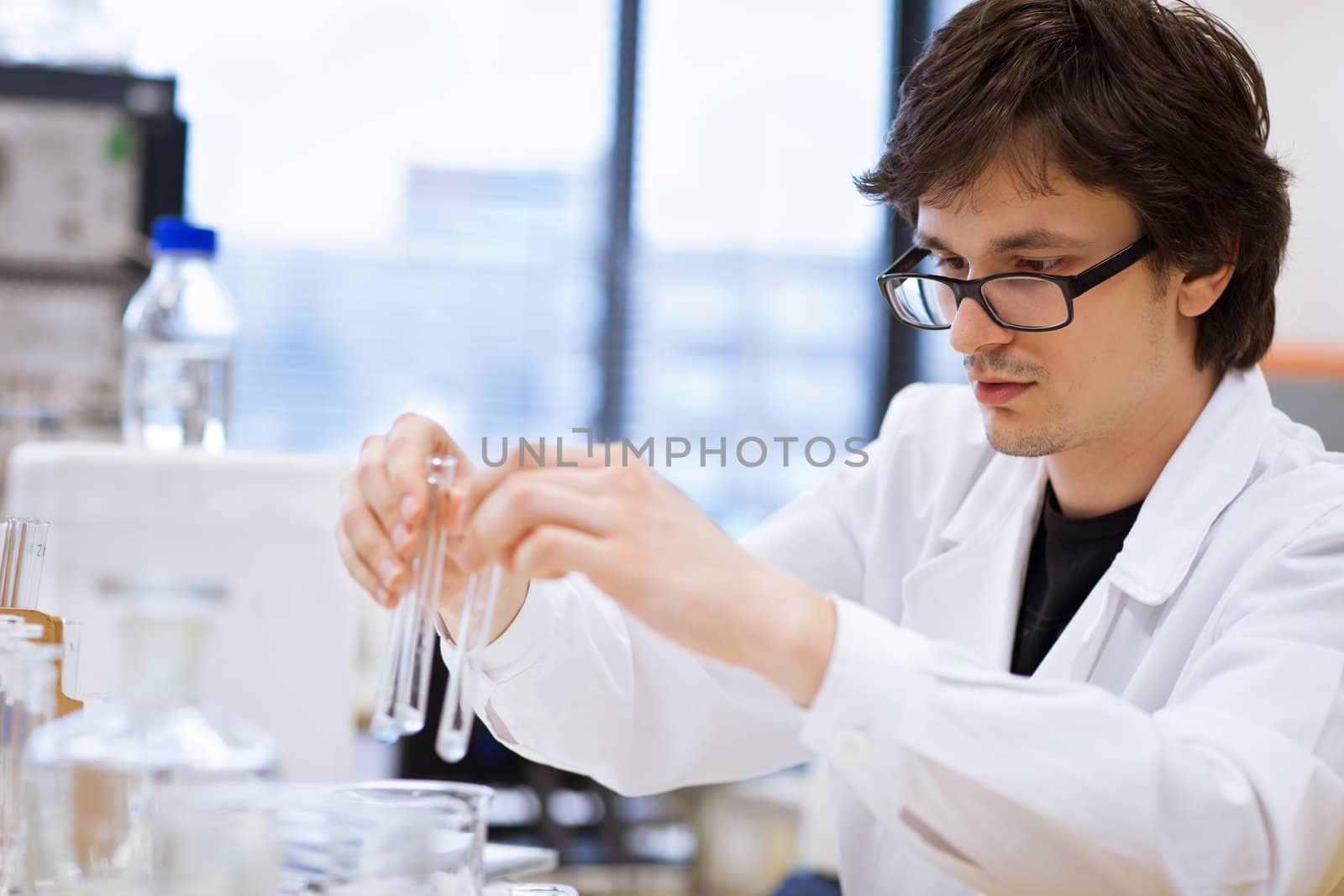 young, male researcher/chemistry student carrying out scientific research in a lab (shallow DOF; color toned image)