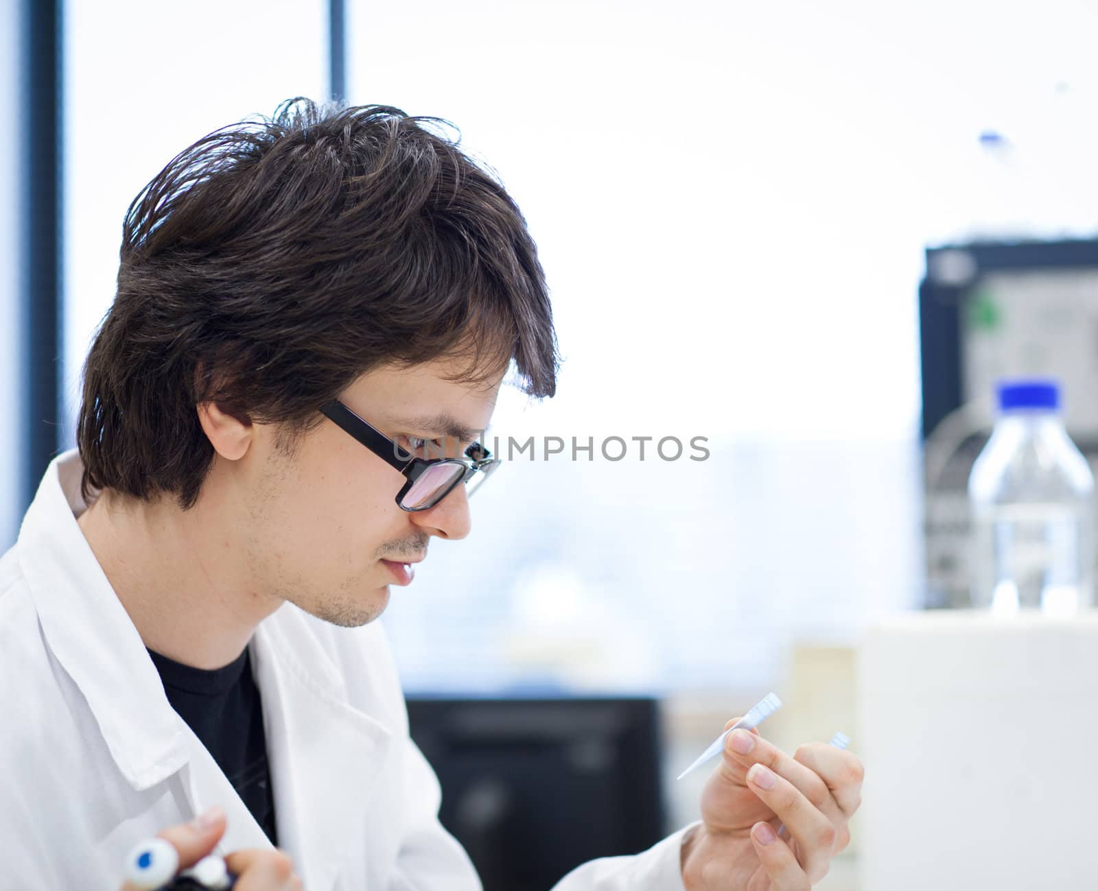 young, male researcher/chemistry student carrying out scientific research in a lab (shallow DOF; color toned image)