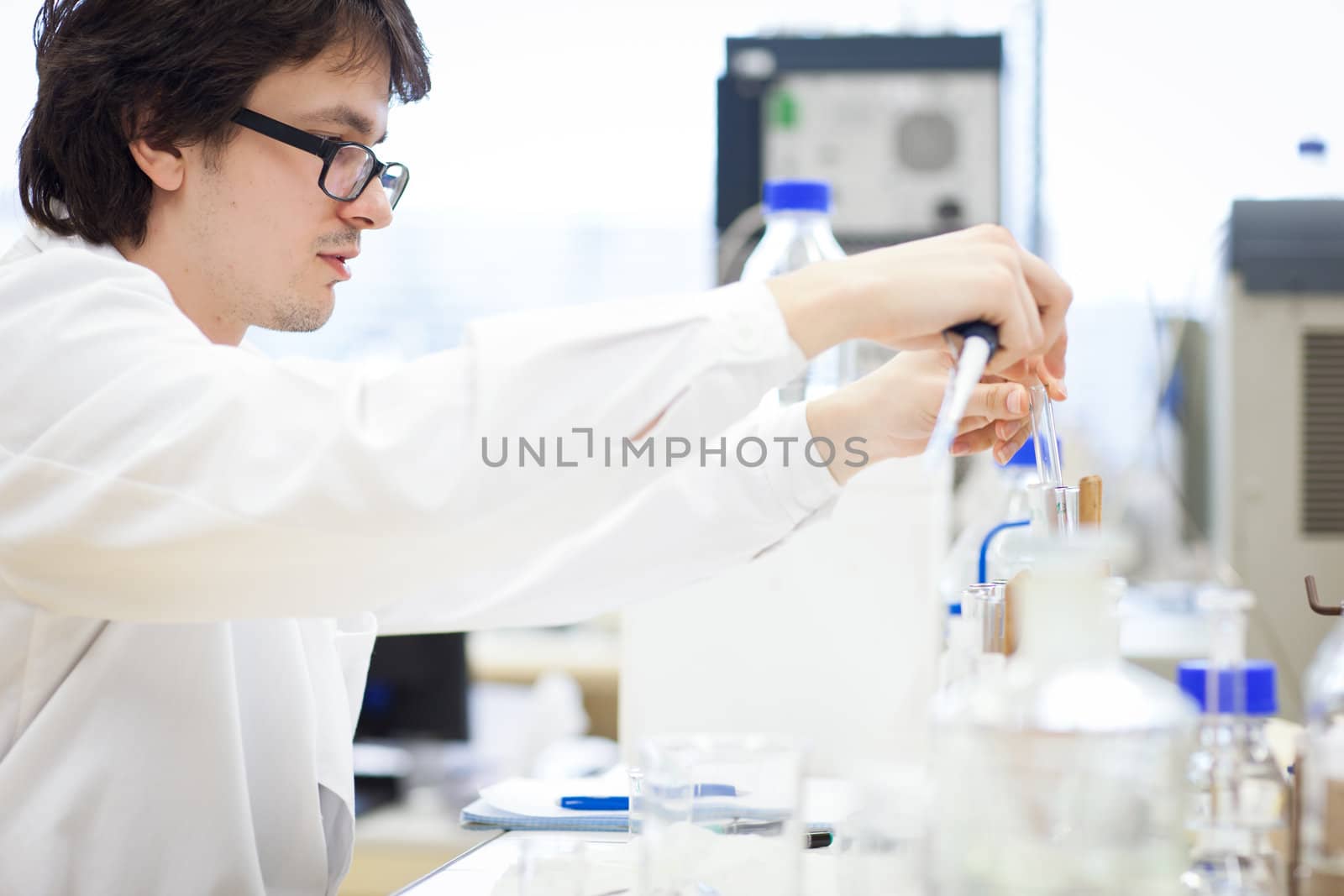 young, male researcher/chemistry student carrying out scientific research in a lab (shallow DOF; color toned image)