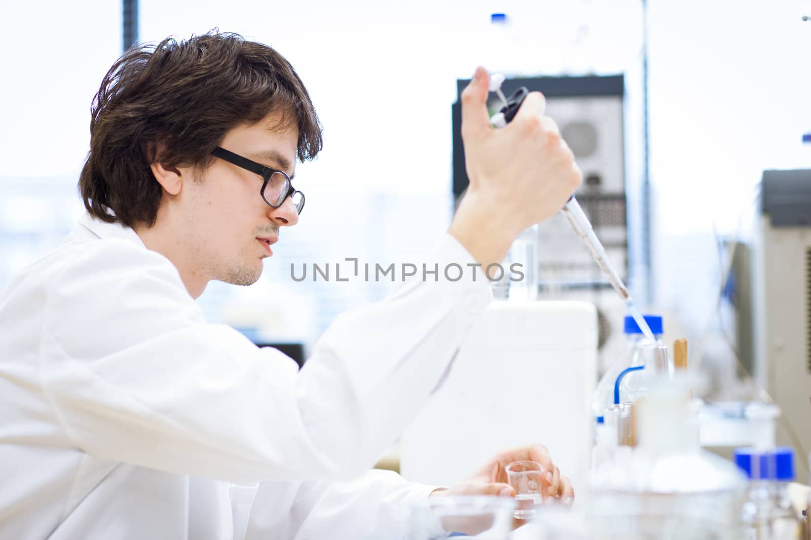 young, male researcher/chemistry student carrying out scientific research in a lab (shallow DOF; color toned image)