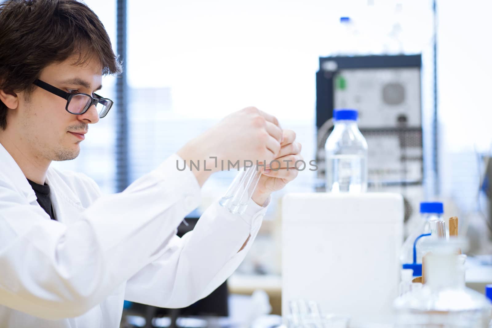 young, male researcher/chemistry student carrying out scientific research in a lab (shallow DOF; color toned image)