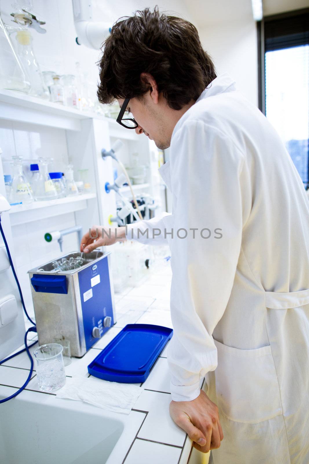 young, male researcher/chemistry student carrying out scientific research in a lab (shallow DOF; color toned image)