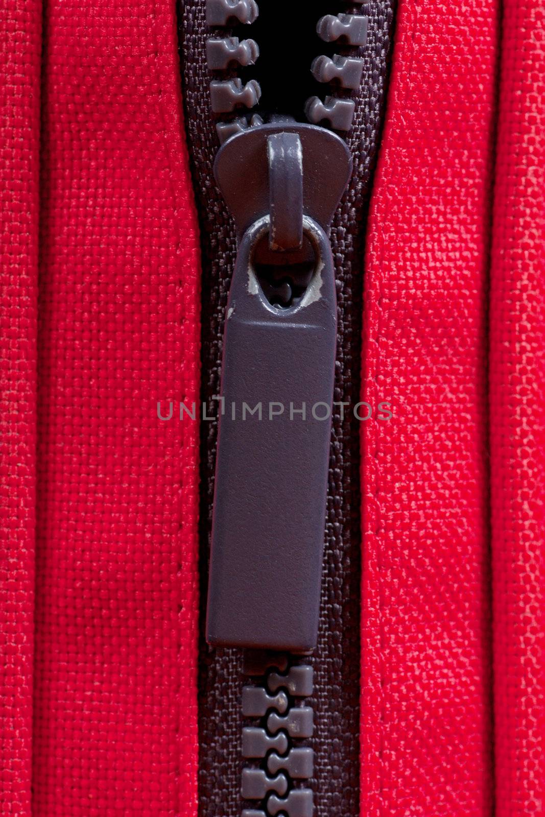 Close-up of a half-opened zipper on a red bag.