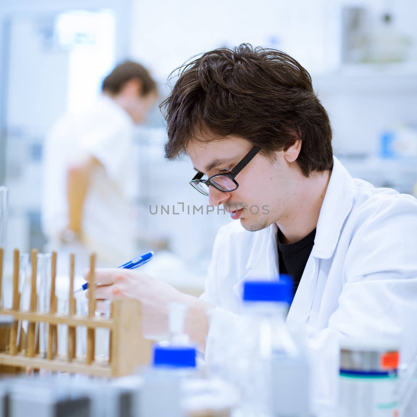 young, male researcher/chemistry student carrying out scientific research in a lab (shallow DOF; color toned image)