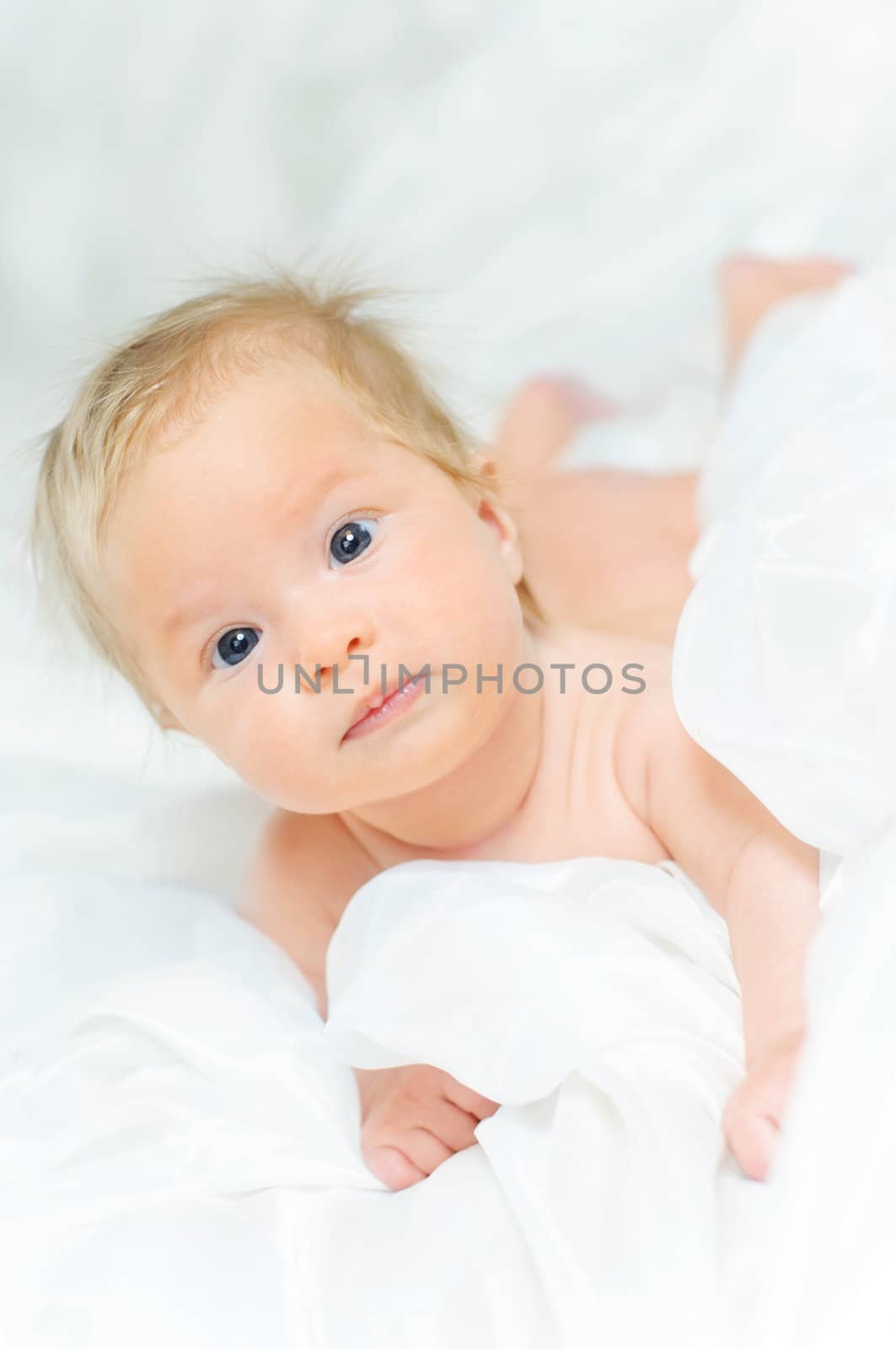 Beautiful baby girl is lying in a bed. by maxoliki