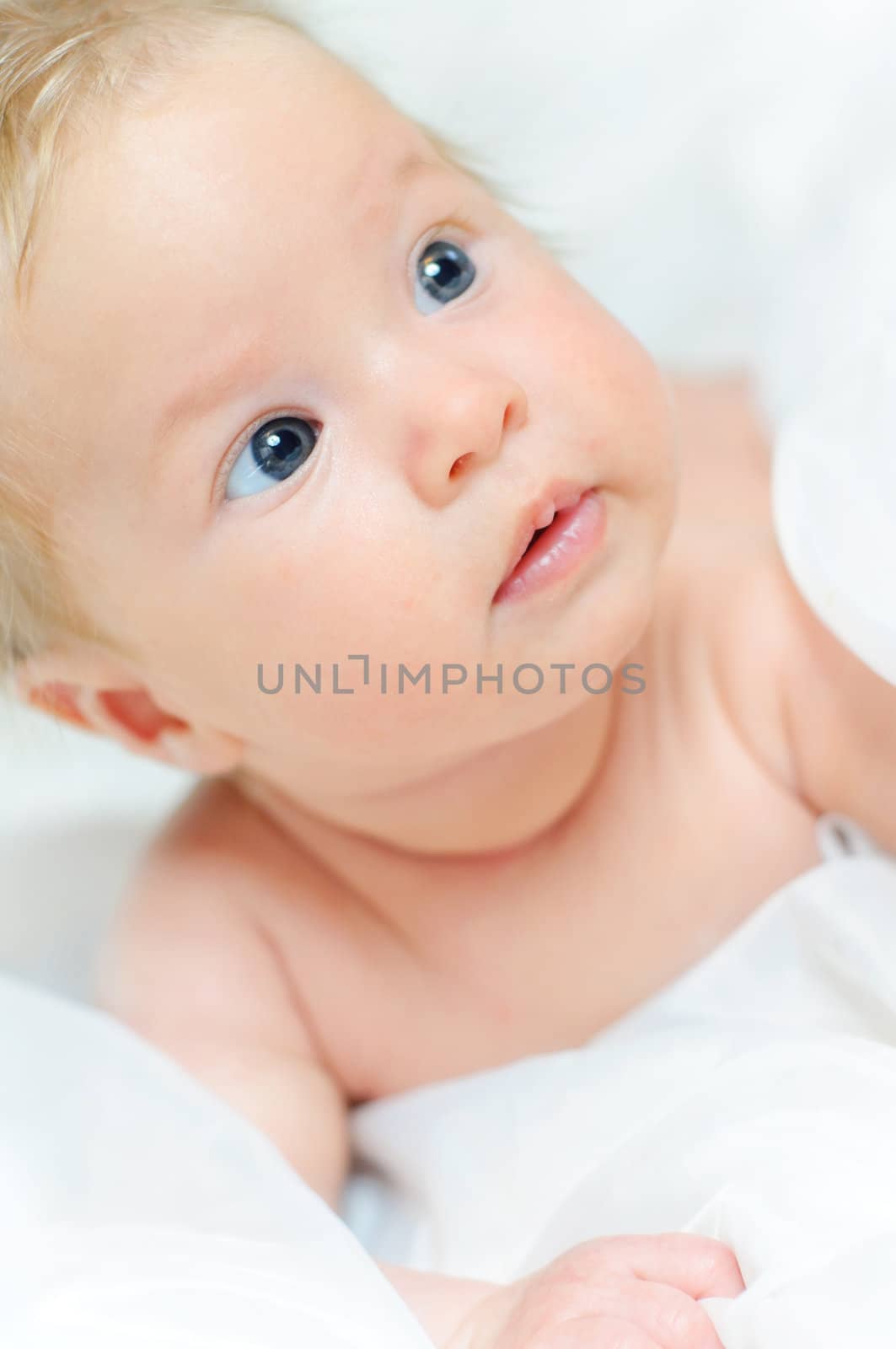 Beautiful cute baby girl is lying in a bed.