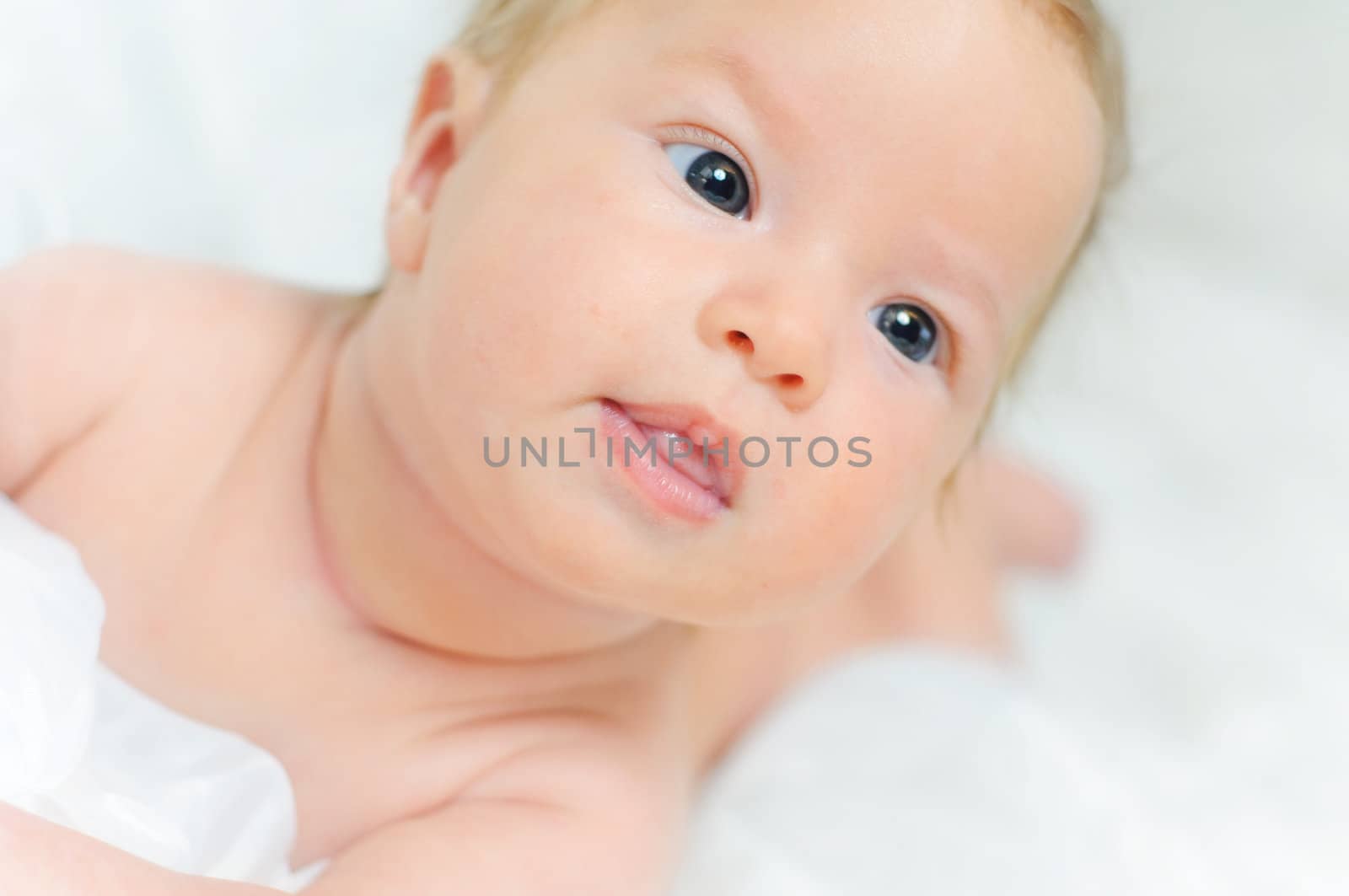 Beautiful cute baby girl is lying in a bed.