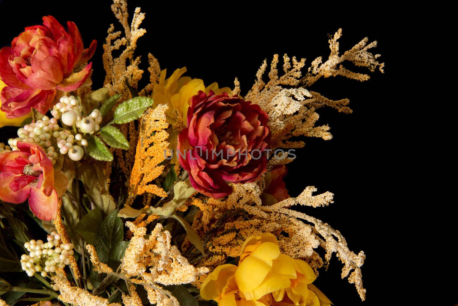A low key photograph of a bunch of artificial flowers on a black background