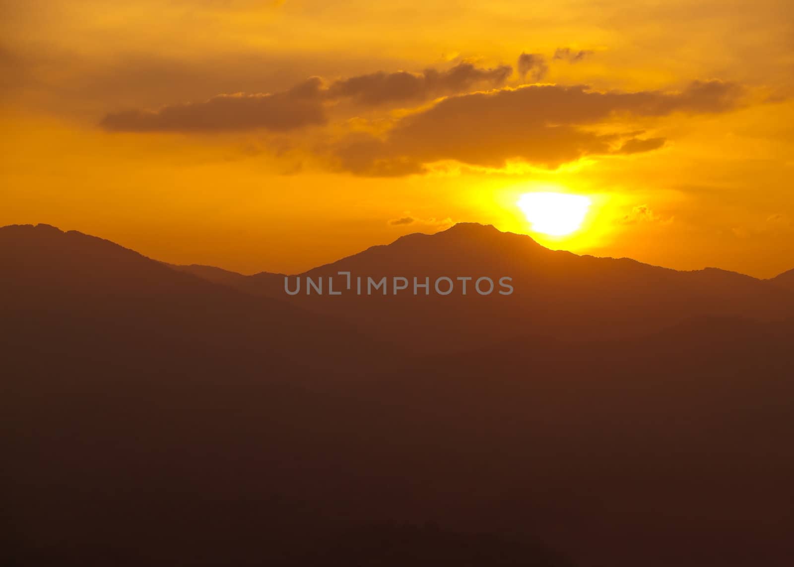 sunset behind the mountains range with orange sky