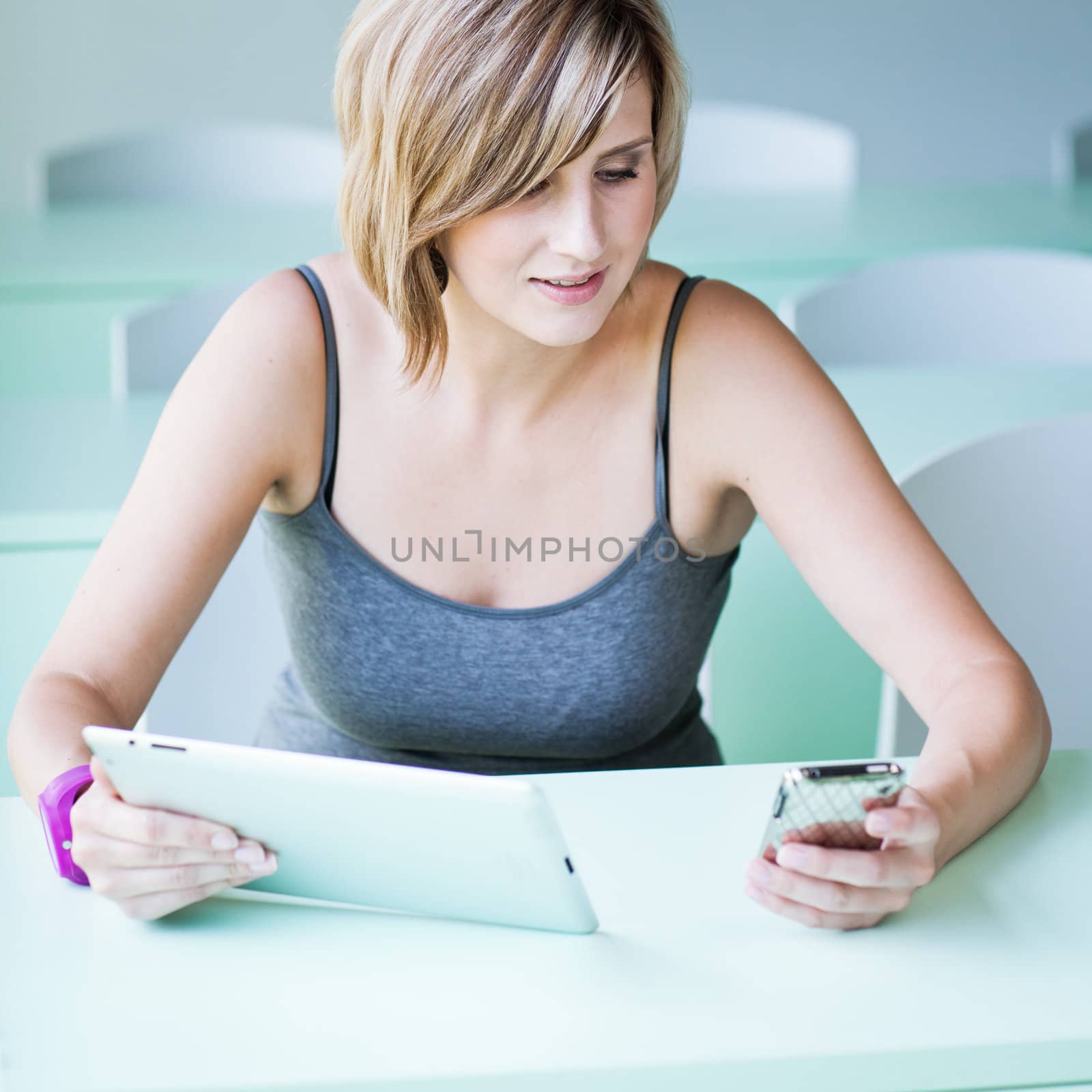 Pretty college student/businesswoman working on her tablet computer (shallow DOF; color toned image)