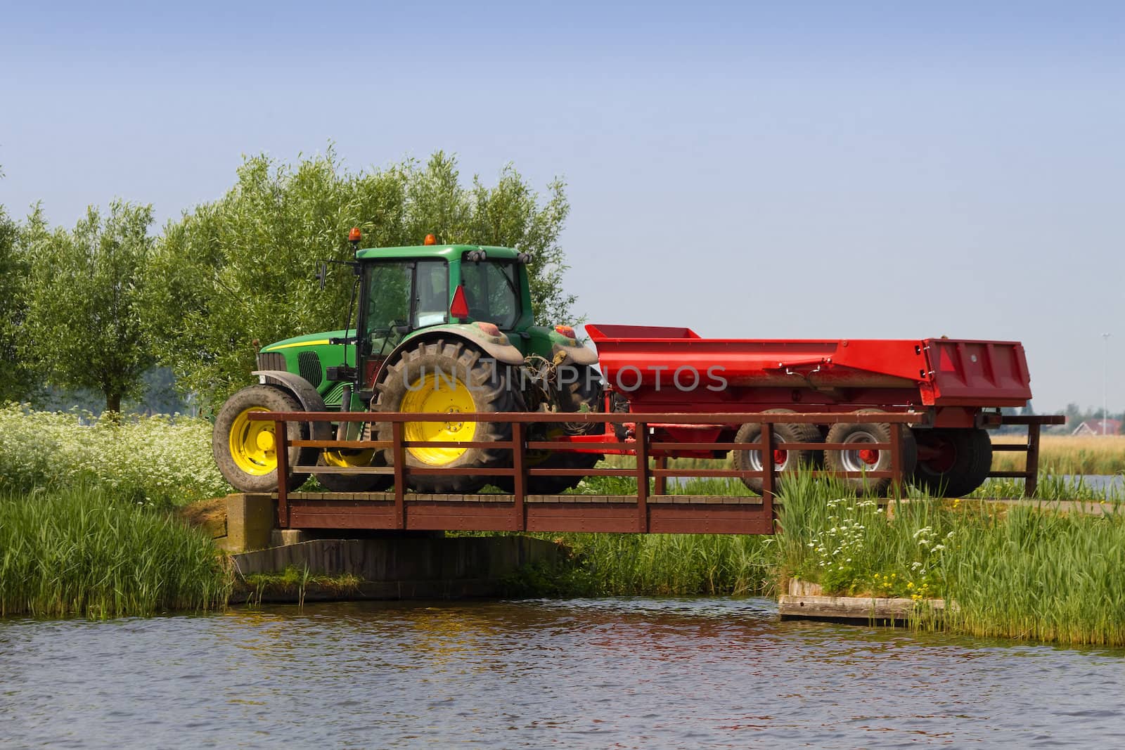 Tractor at work driving on country road and over bridge