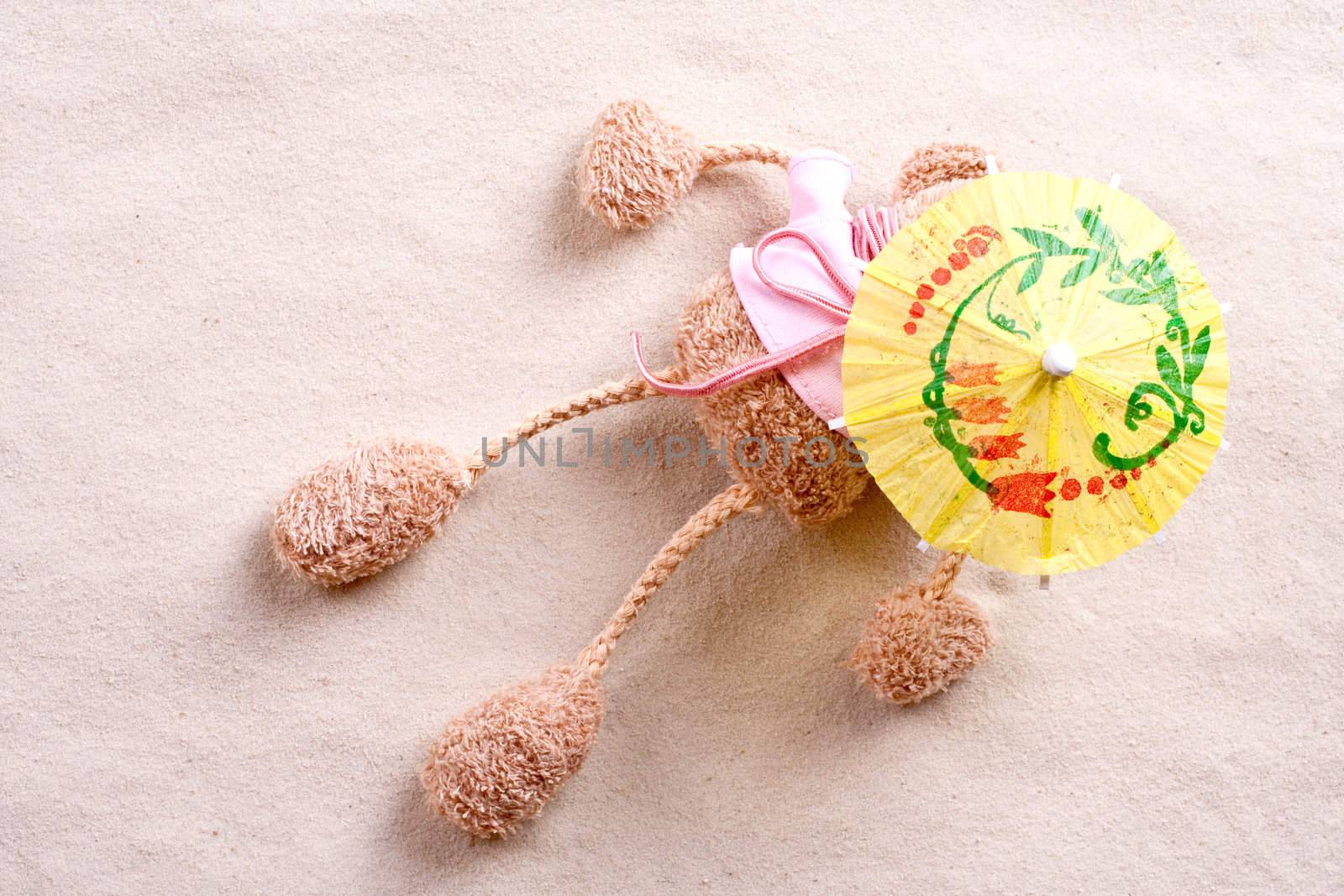 plush toy under the beach umbrella on the sand