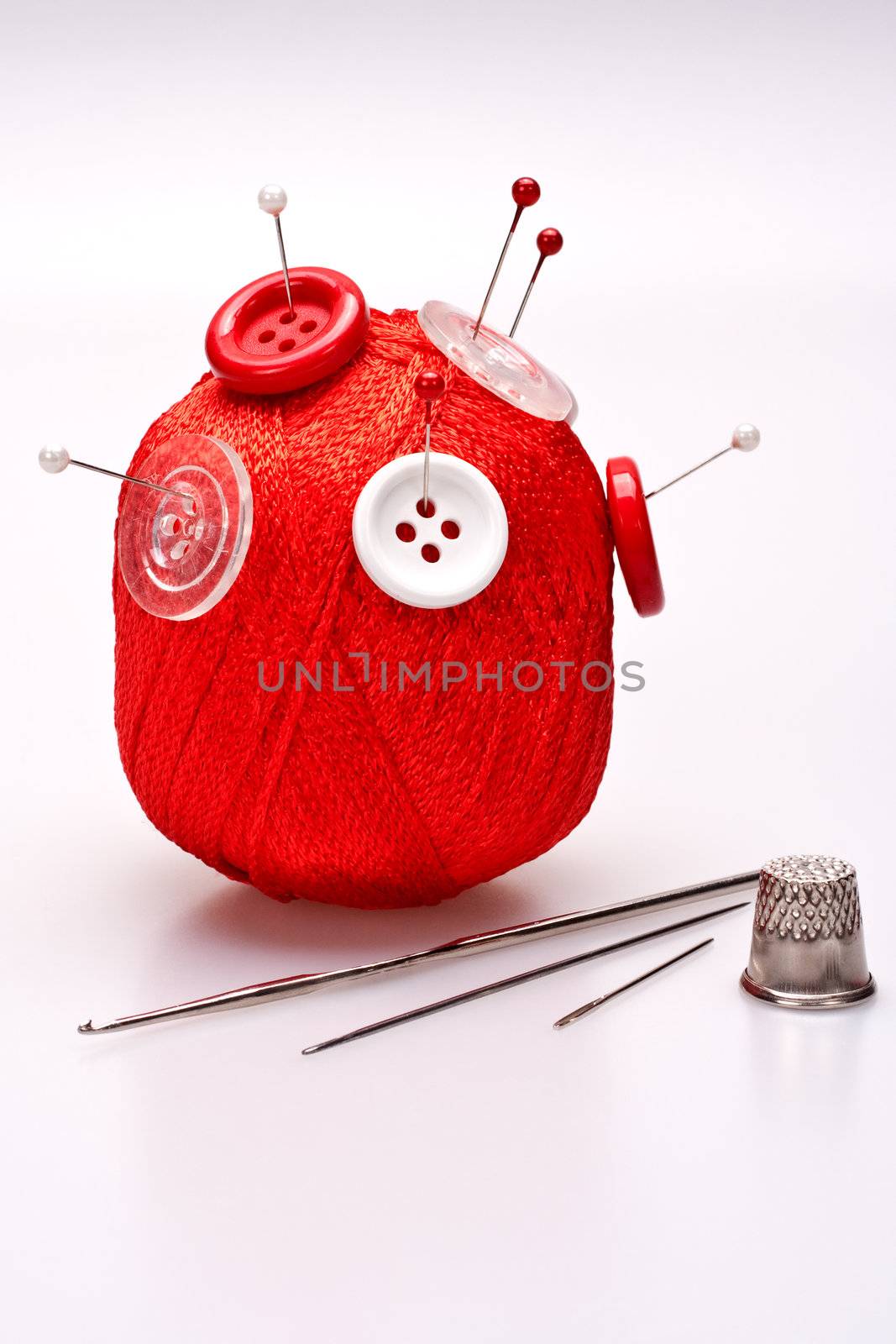 red and white pins in red wool ball with buttons