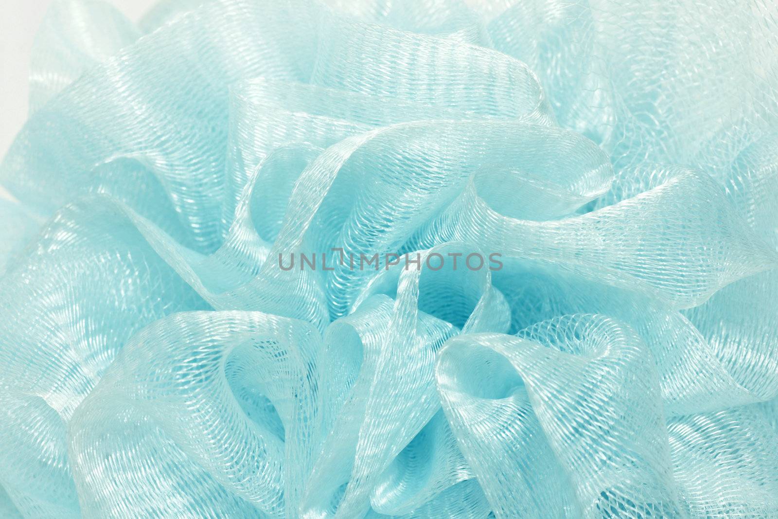 Textured background abstract: detailed macro of alight blue shower puff made of meshed nylon forming multiple diamond shape patterns.