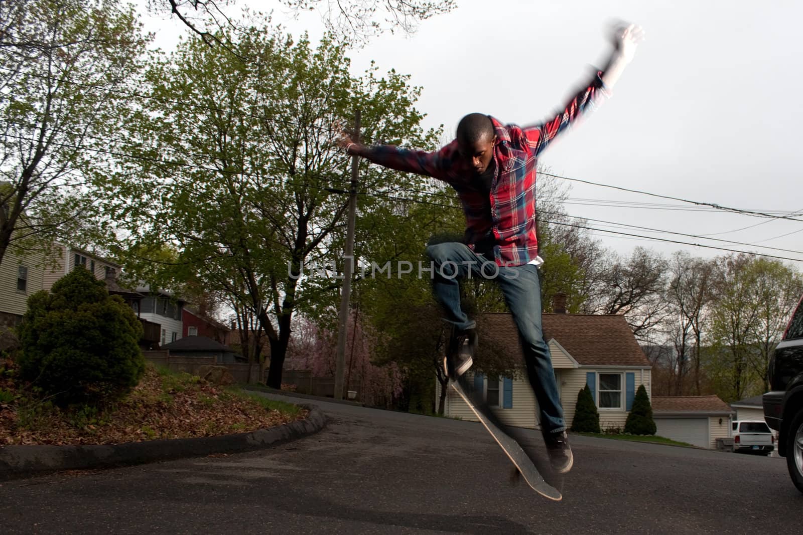 A skateboarder performs jumps or ollies on asphalt.  Slight motion blur showing the movement on the arms and legs.