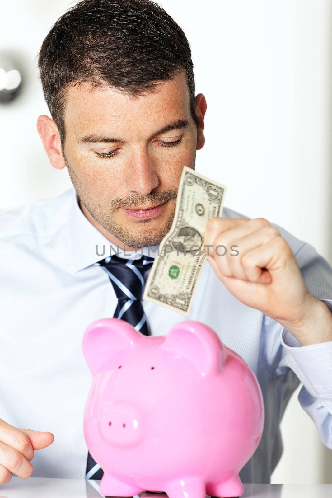 young man with pink piggy bank and bill