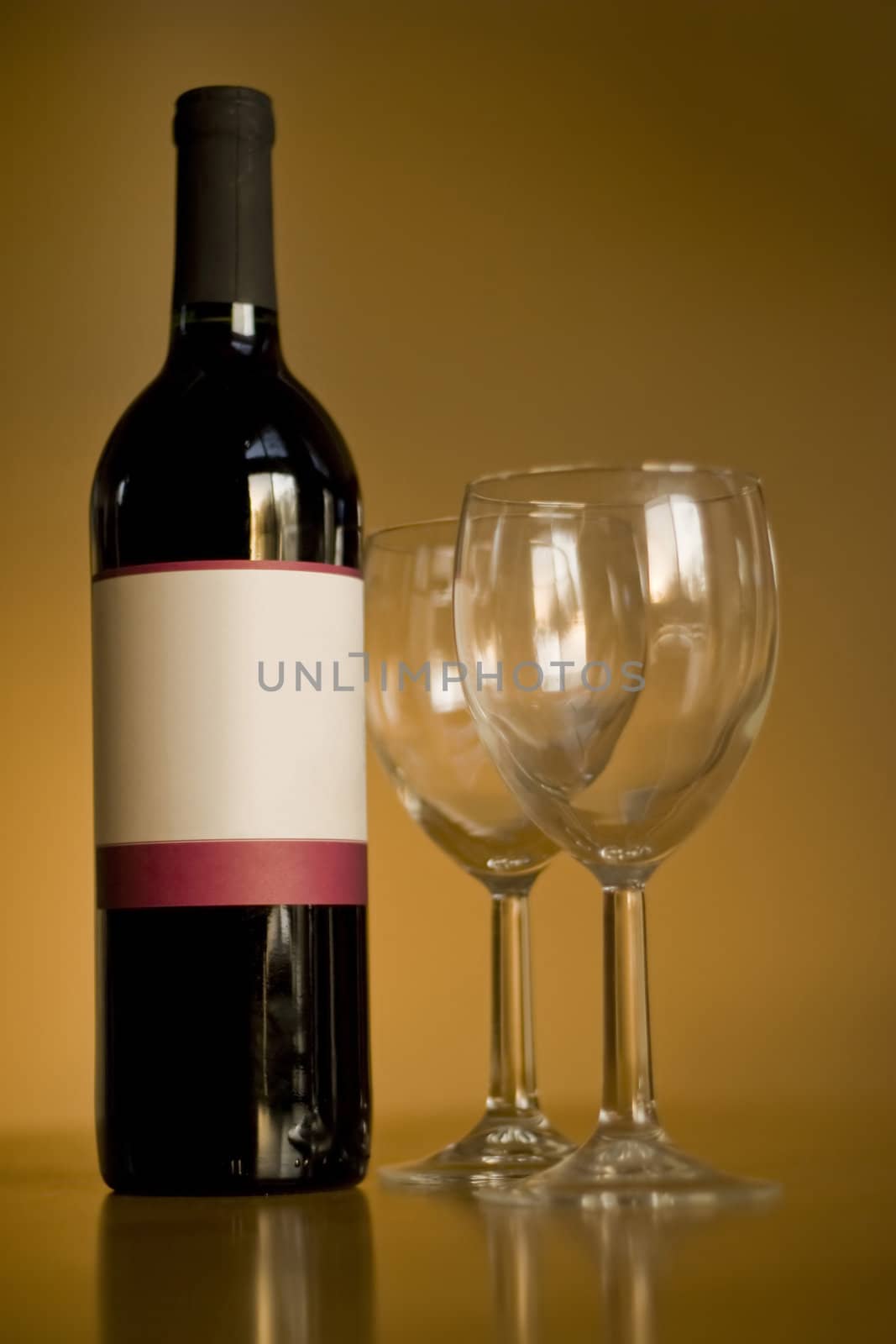 A still life shot of a single wine bottle and a pair of empty glasses.  The label provides copy space for any logo or type desired.