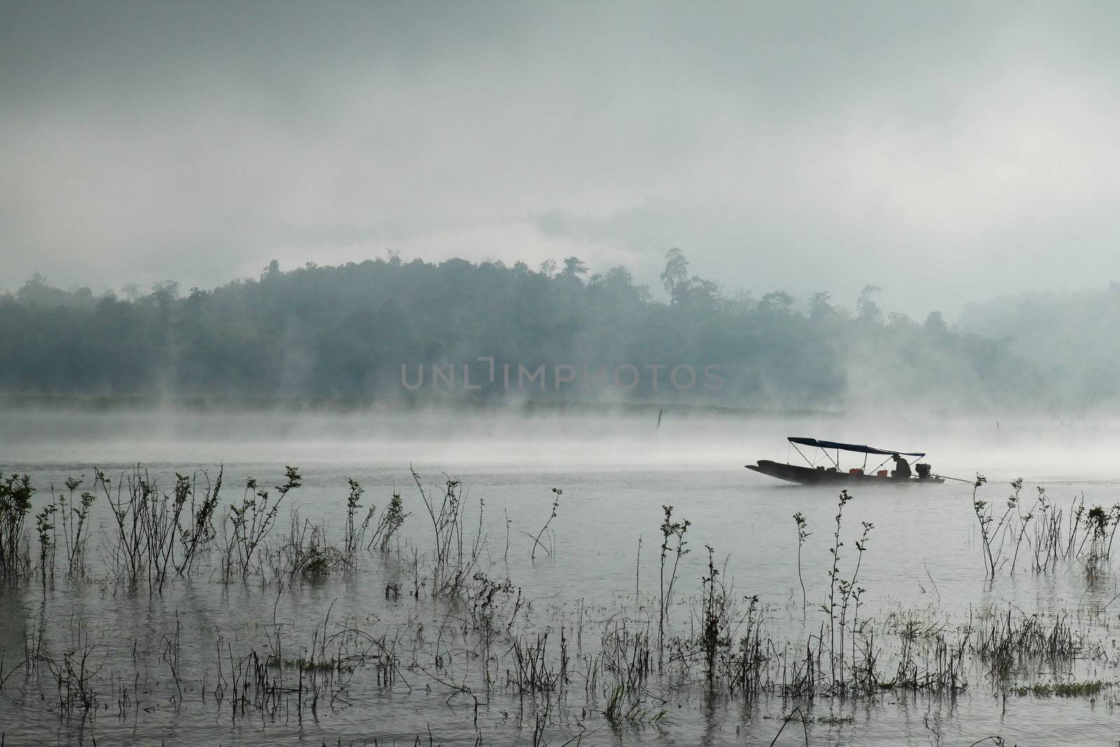 A man rowing his boat in Sangkhlaburi, thailand by nuchylee