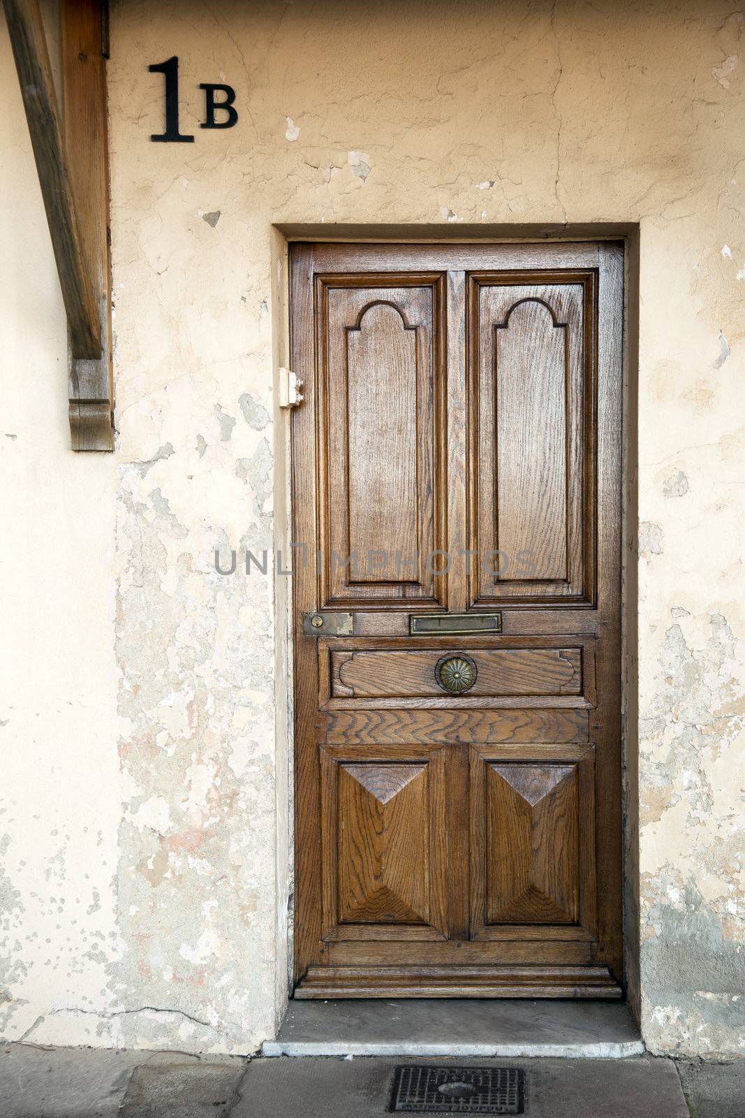 Old wooden door in weathered building with house number 1B.