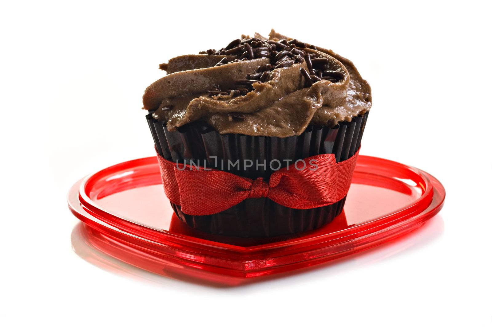 Chocolate cupcake with red bow on a heart shaped plate