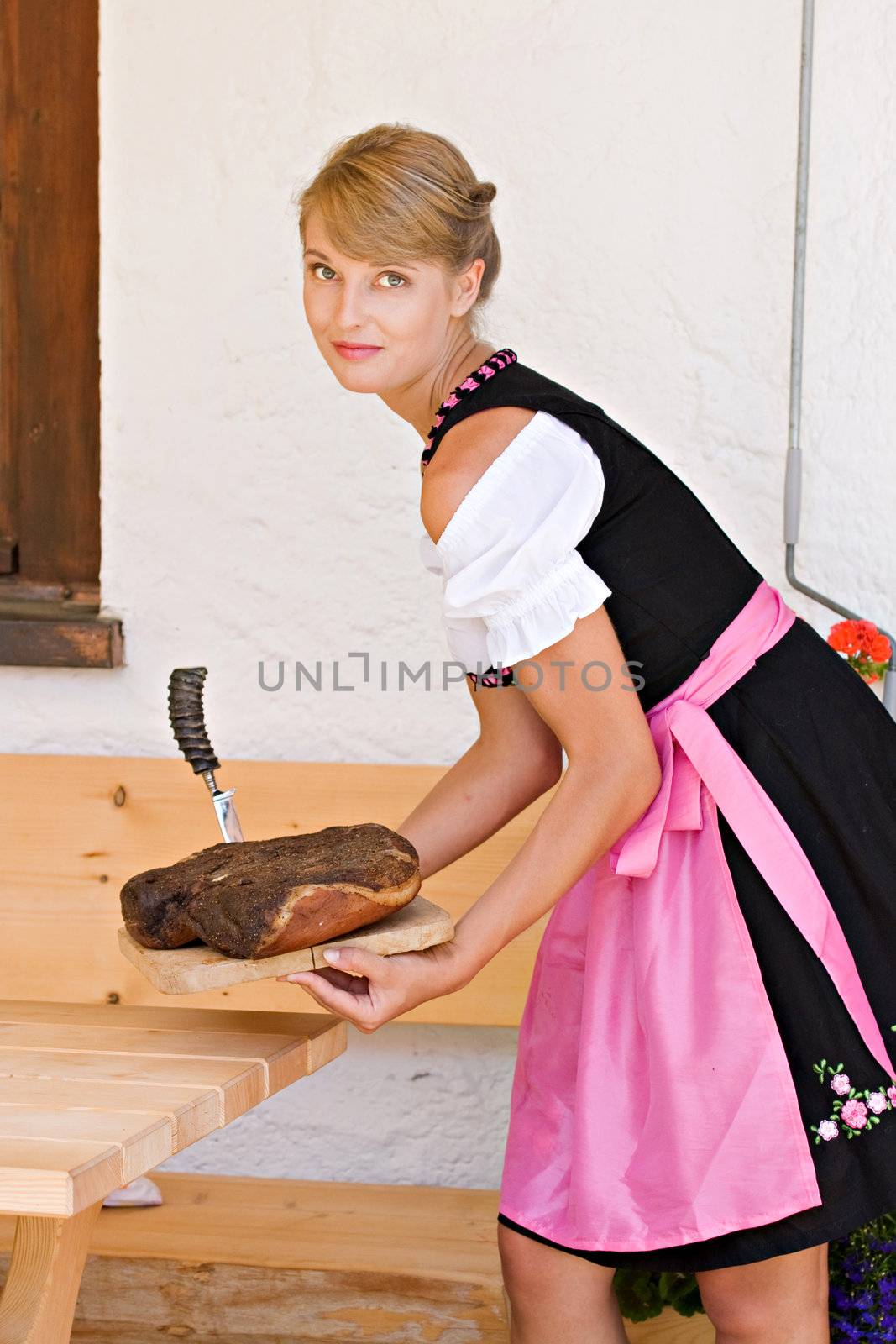 Bavarian Dirndl woman serving a bacon on a plate Alm