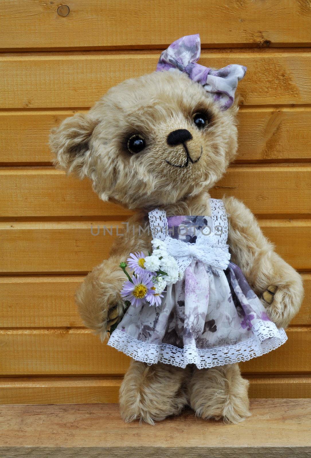 Handmade, the sewed toy: teddy bear Lucky before a wooden wall