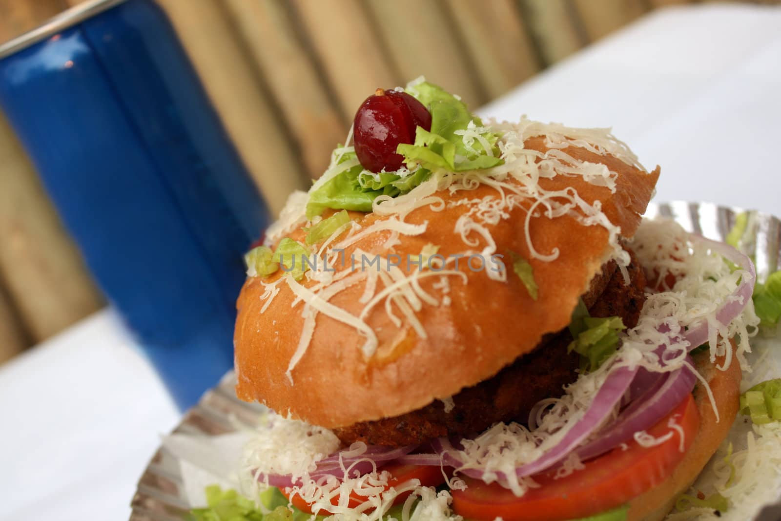 A scrumptious chicken burger with a blue soda can.