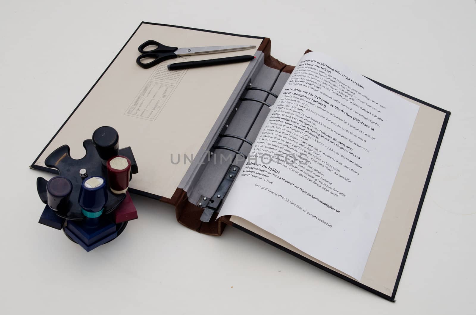 ring binder with paper, scissors, pen, stamps and paper on a desk