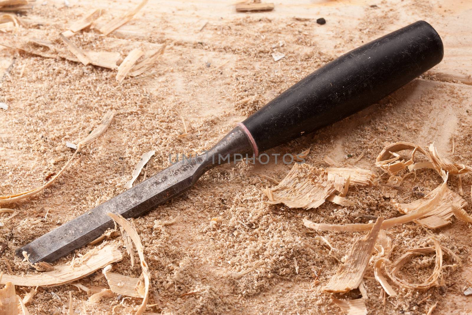tools series: steel chisel on wooden plank with shaving