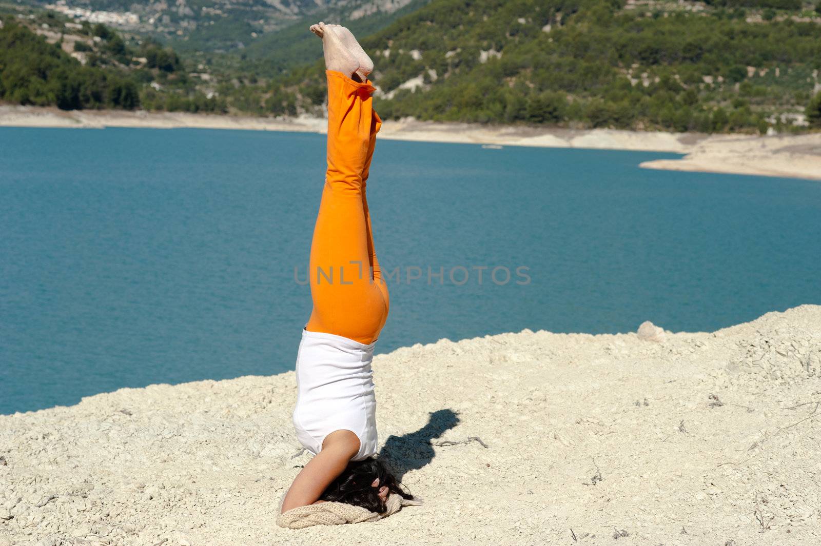 Fit and balanced woman doing a yoga handstand outdoors