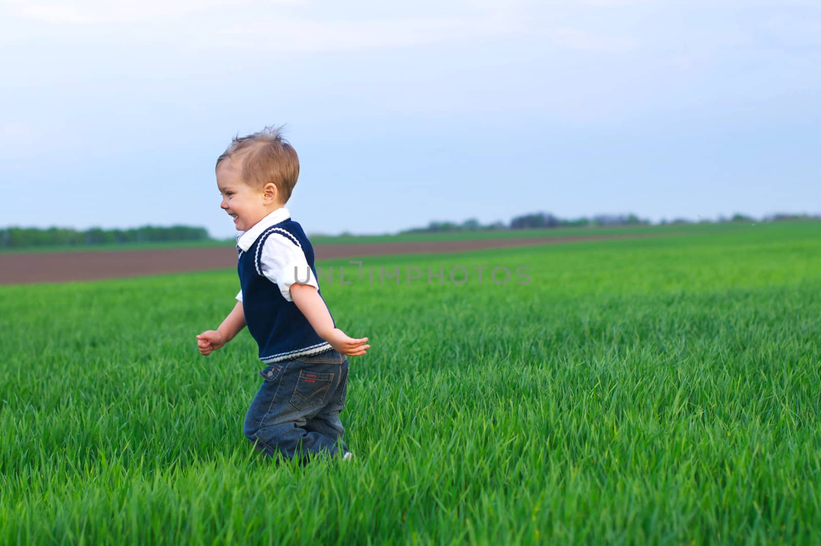 A beautiful little boy runing in the grass by maxoliki