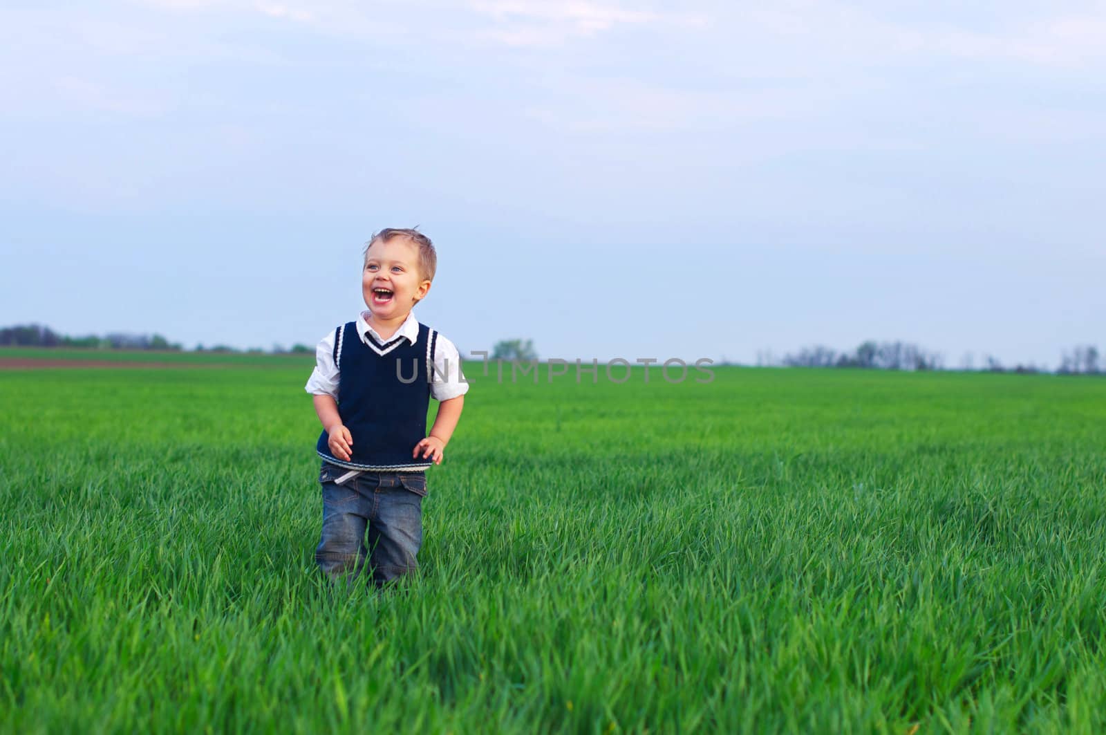 A beautiful little boy staing in the grass by maxoliki