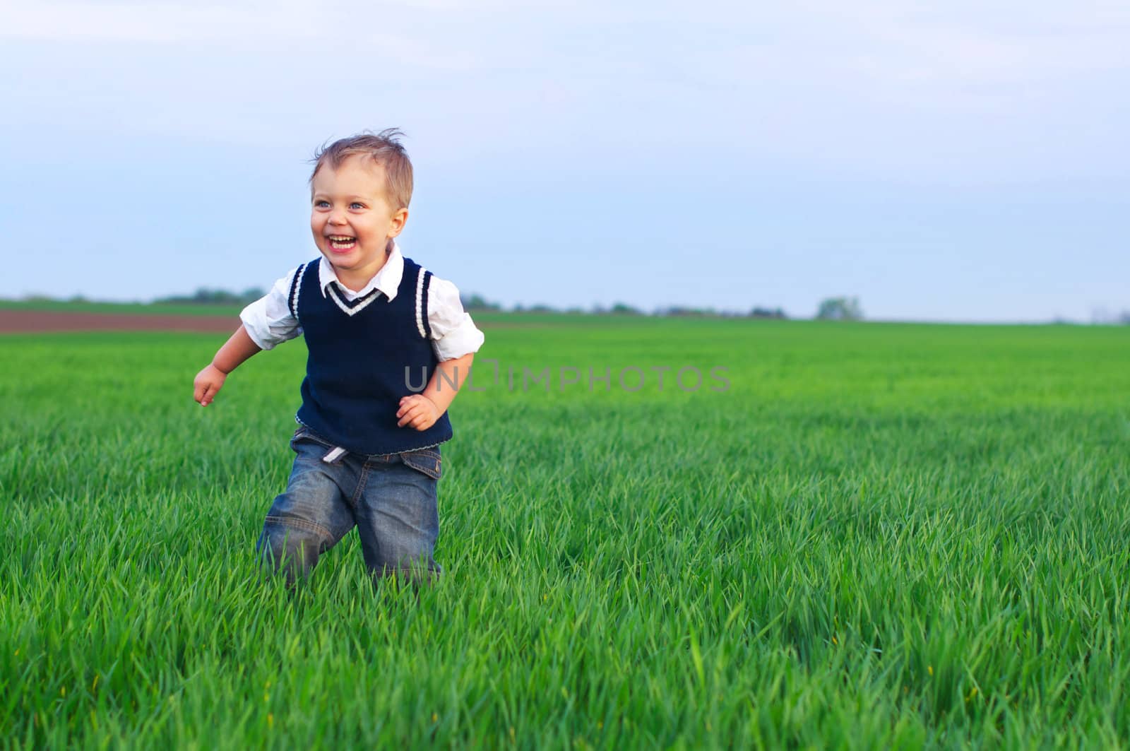 A beautiful little baby boy runing in the grass