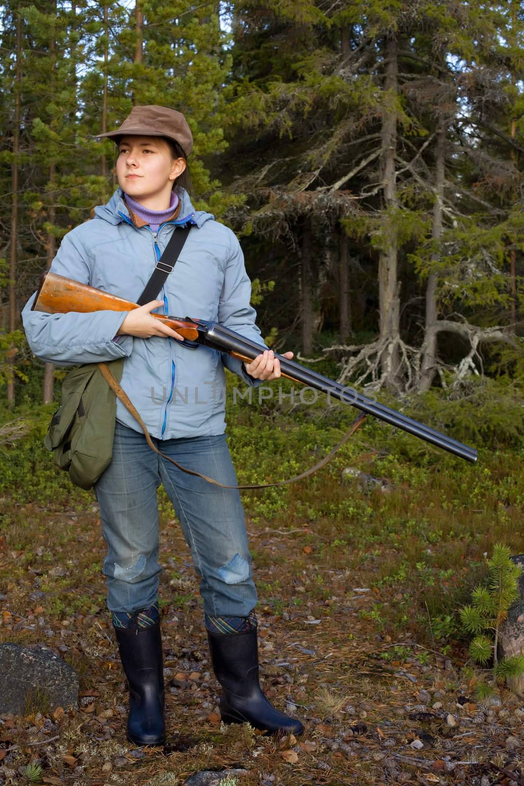 Girl with a shotgun in the autumn forest