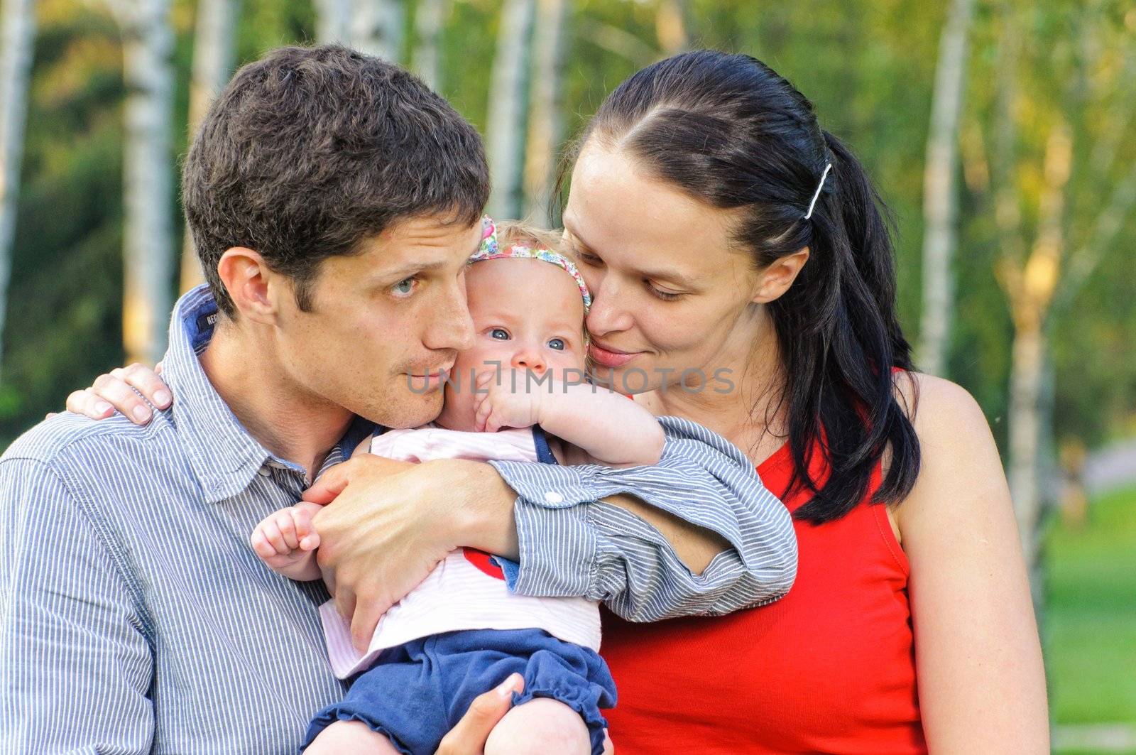 Happy mom and dad with their little daughter for a walk in the park