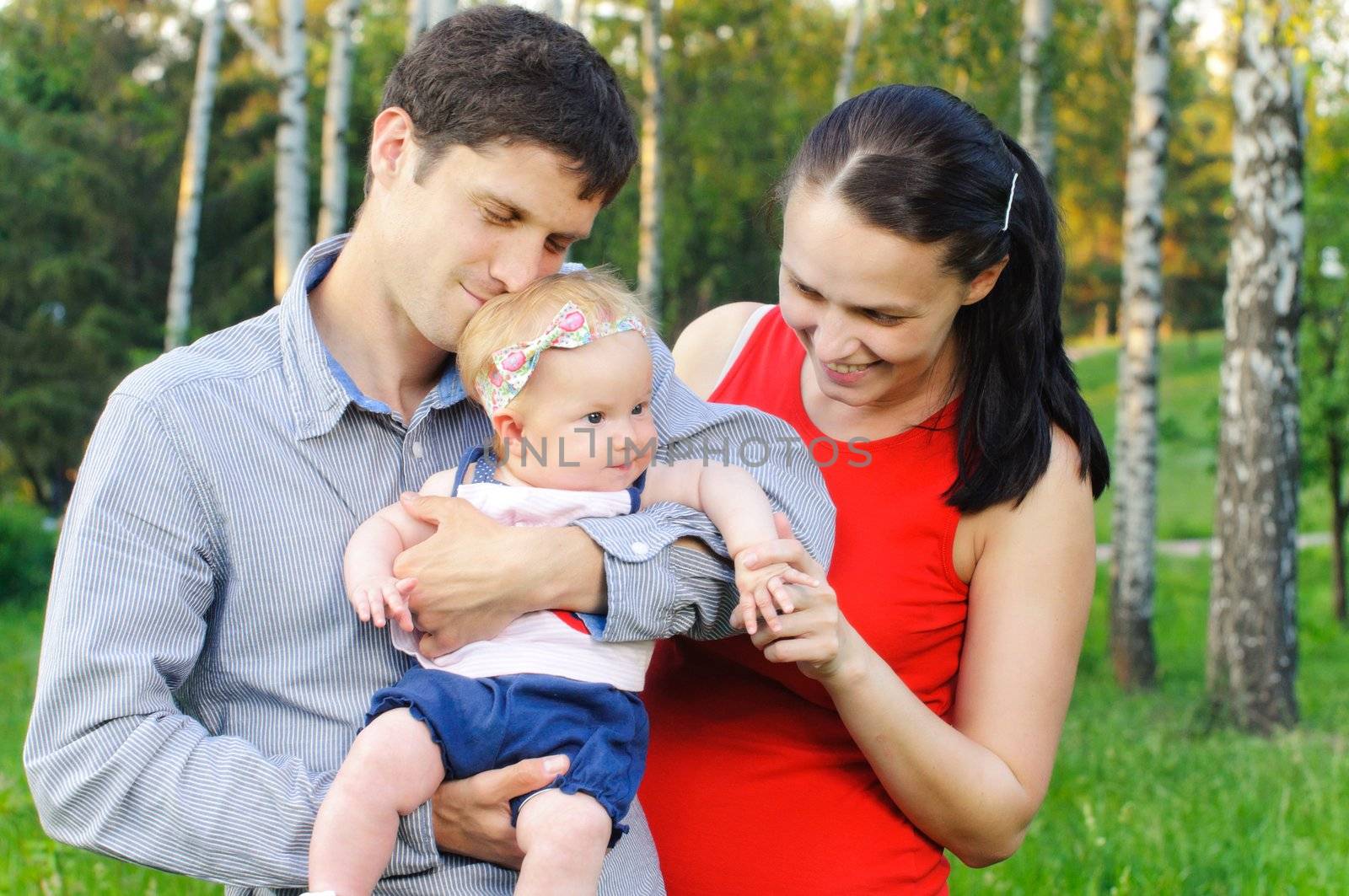 Happy mom and dad with their little daughter for a walk in the park