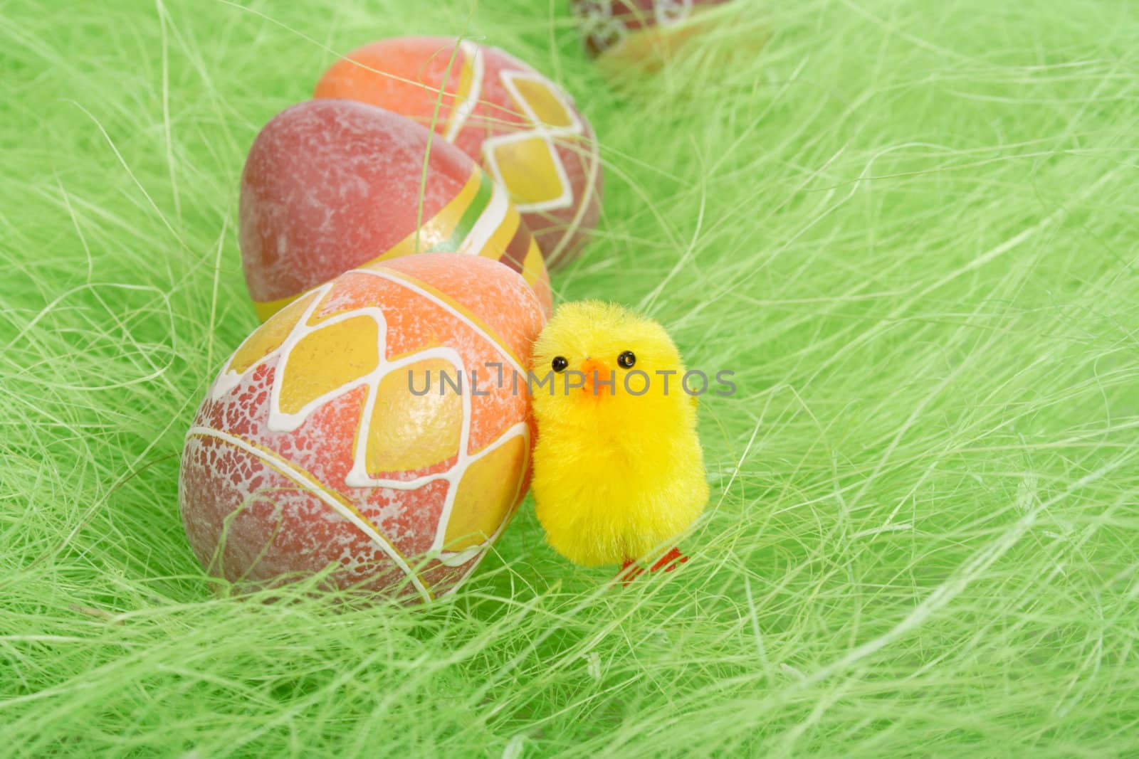 Easter chick and Painted Colorful Easter Egg on green Grass