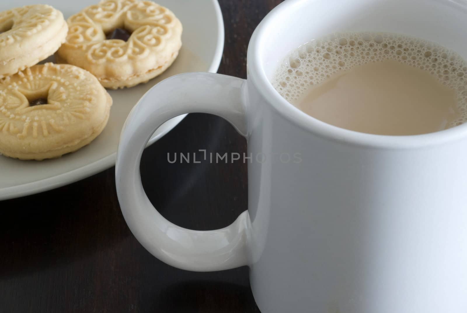 a mug of white tea and plate jam biscuits