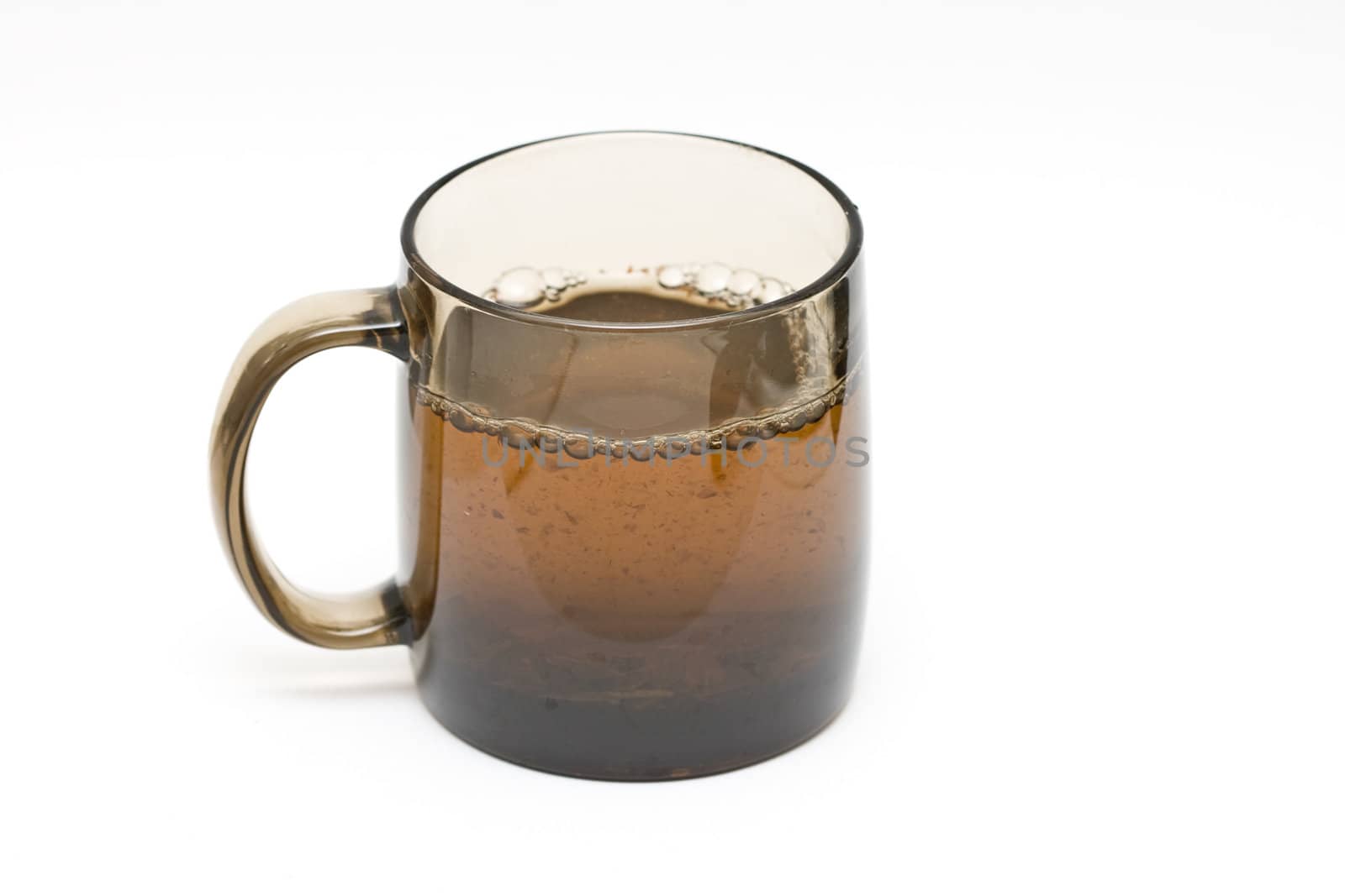 a transparent black cup with tea and tealeafs