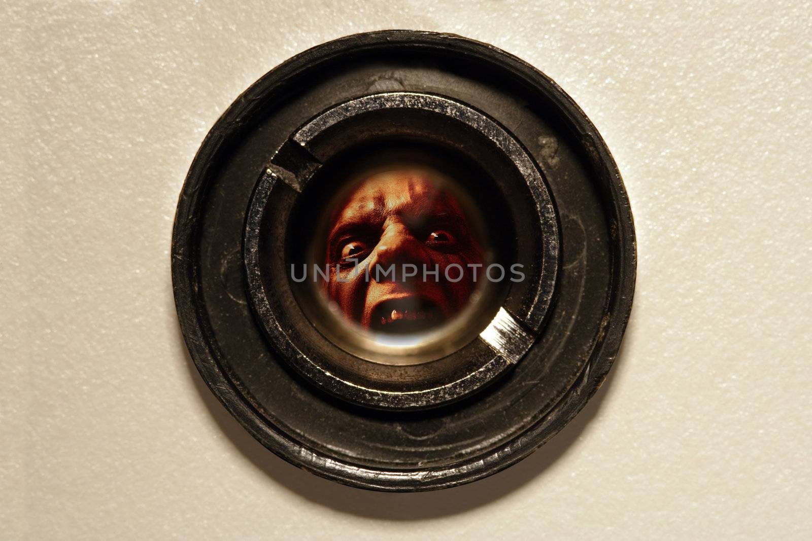 Looking through the peephole of an apartment door at an angry fellow on the other side.
