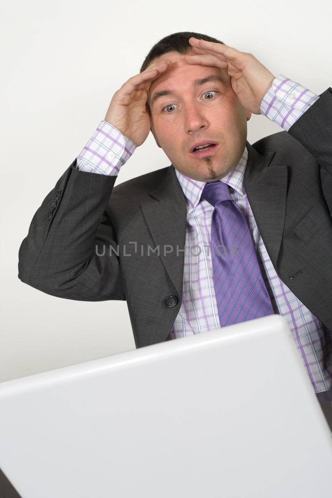 Horrified businessman in his thirties looking at a bad thing on his laptop.
