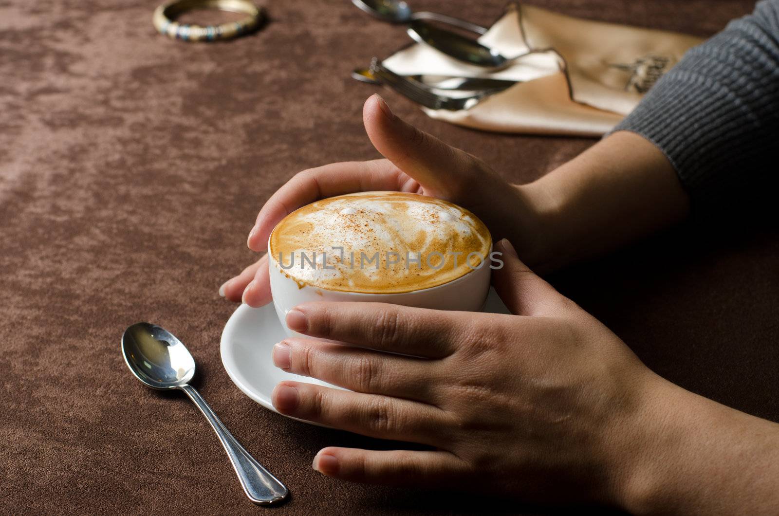 Closeup of female hands holding cup of Cappuccino