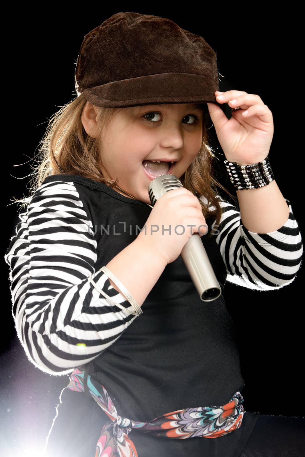 A stylish little girl is sing into a microphone, shot with a backlight