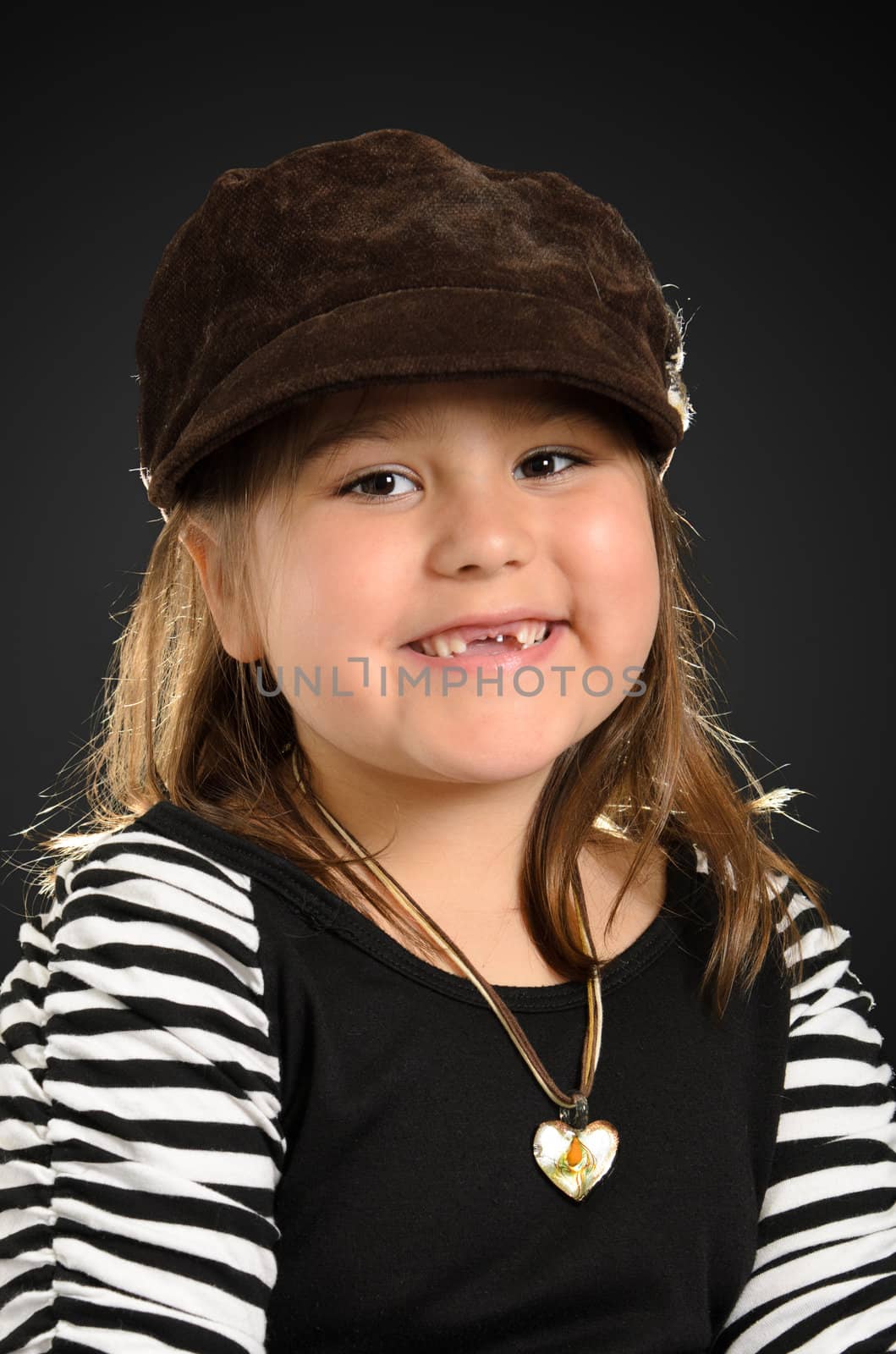 Portrait of a kindergarten girl smiling and wearing stylish clothes, shot with a backlight.