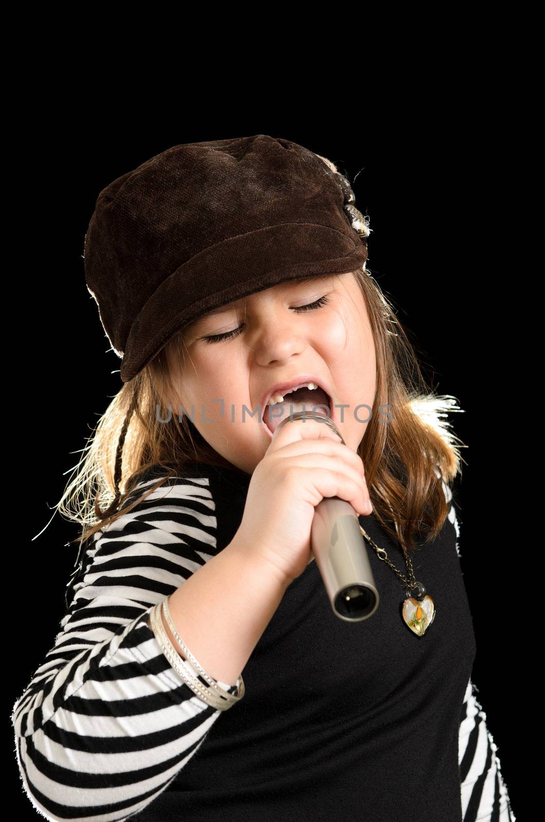 A young girl is singing like a pop star, isolated against a black background.