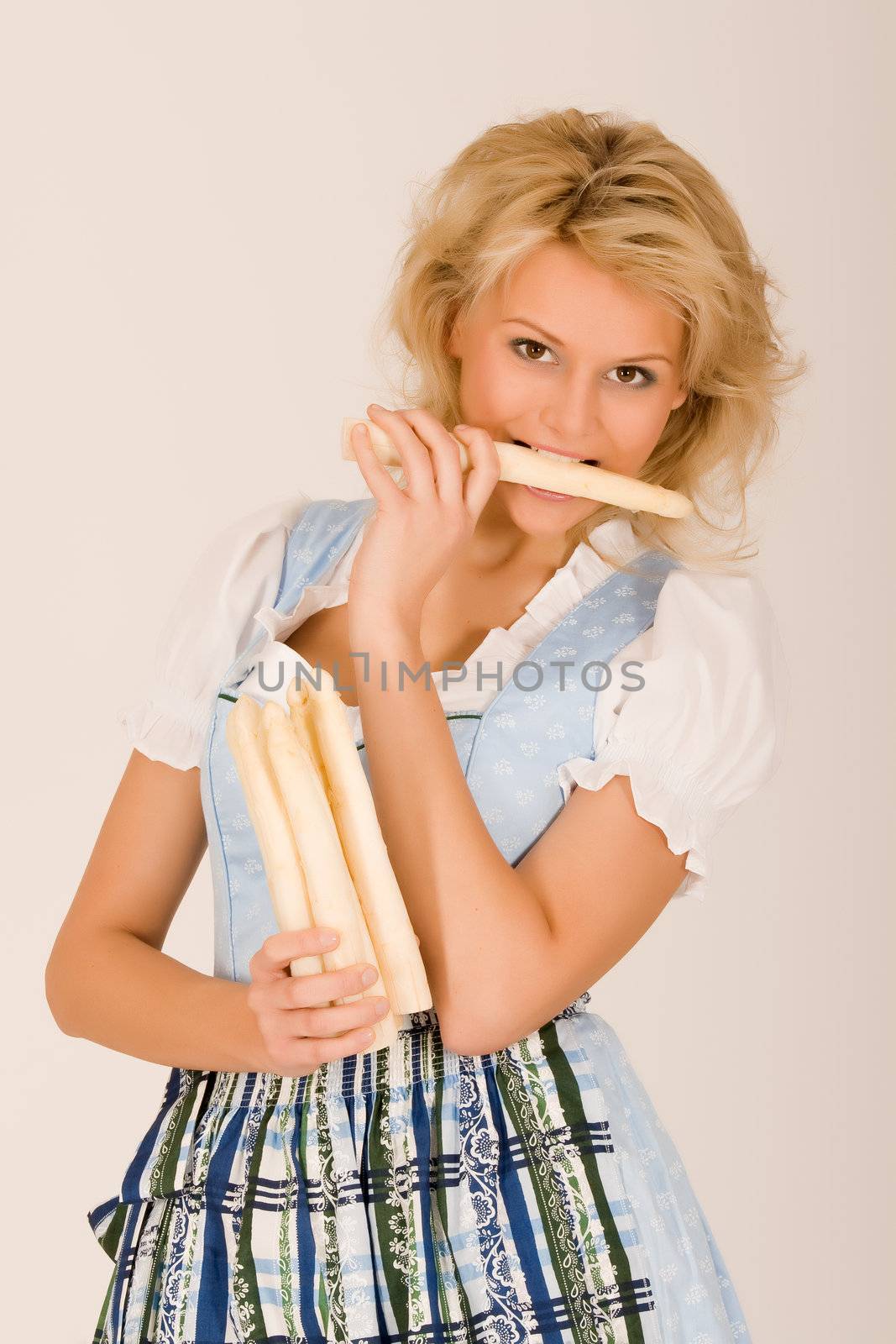 Beauty in Bavarian costume with asparagus in her hand