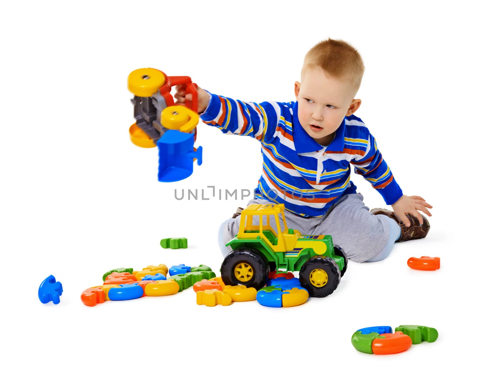 Little boy playing actively with plastic toys sitting on the floor