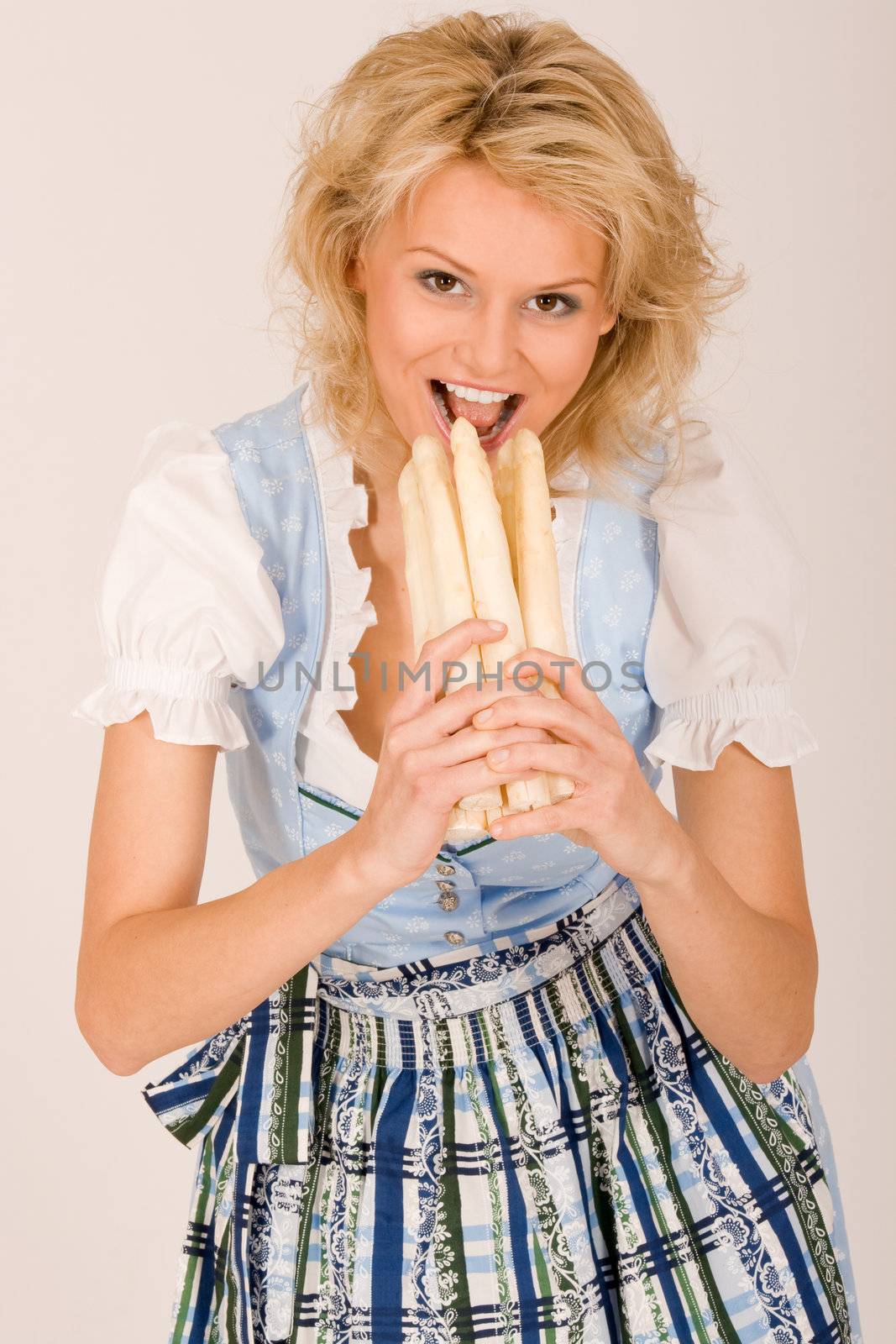 Beauty in Bavarian costume with asparagus in her hand