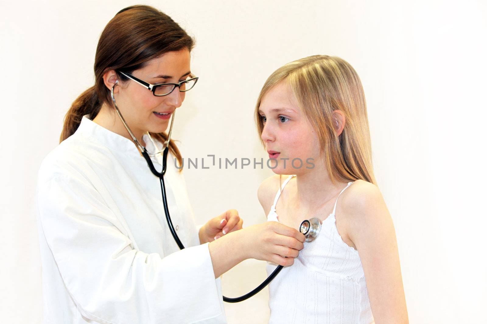 Nurse or doctor examines a child with stethoscope against white background - Copy Space