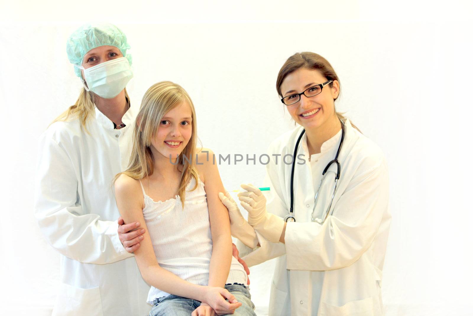 A child is examined by a friendly team of doctors and receives an injection or vaccination - all looking towards the camera and smile